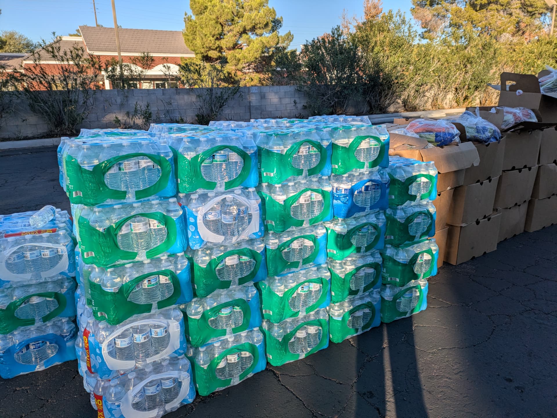 Cases of bottled water stacked beside cardboard boxes of supplies