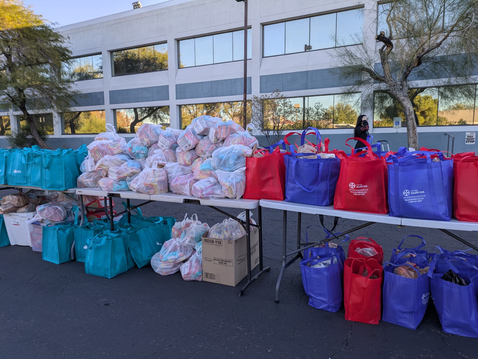 Colorful grocery bags and packaged food arranged on tables outdoors