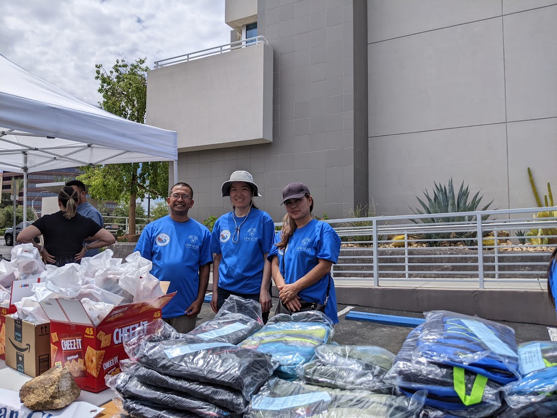 Volunteers stand behind a table of backpacks and snacks