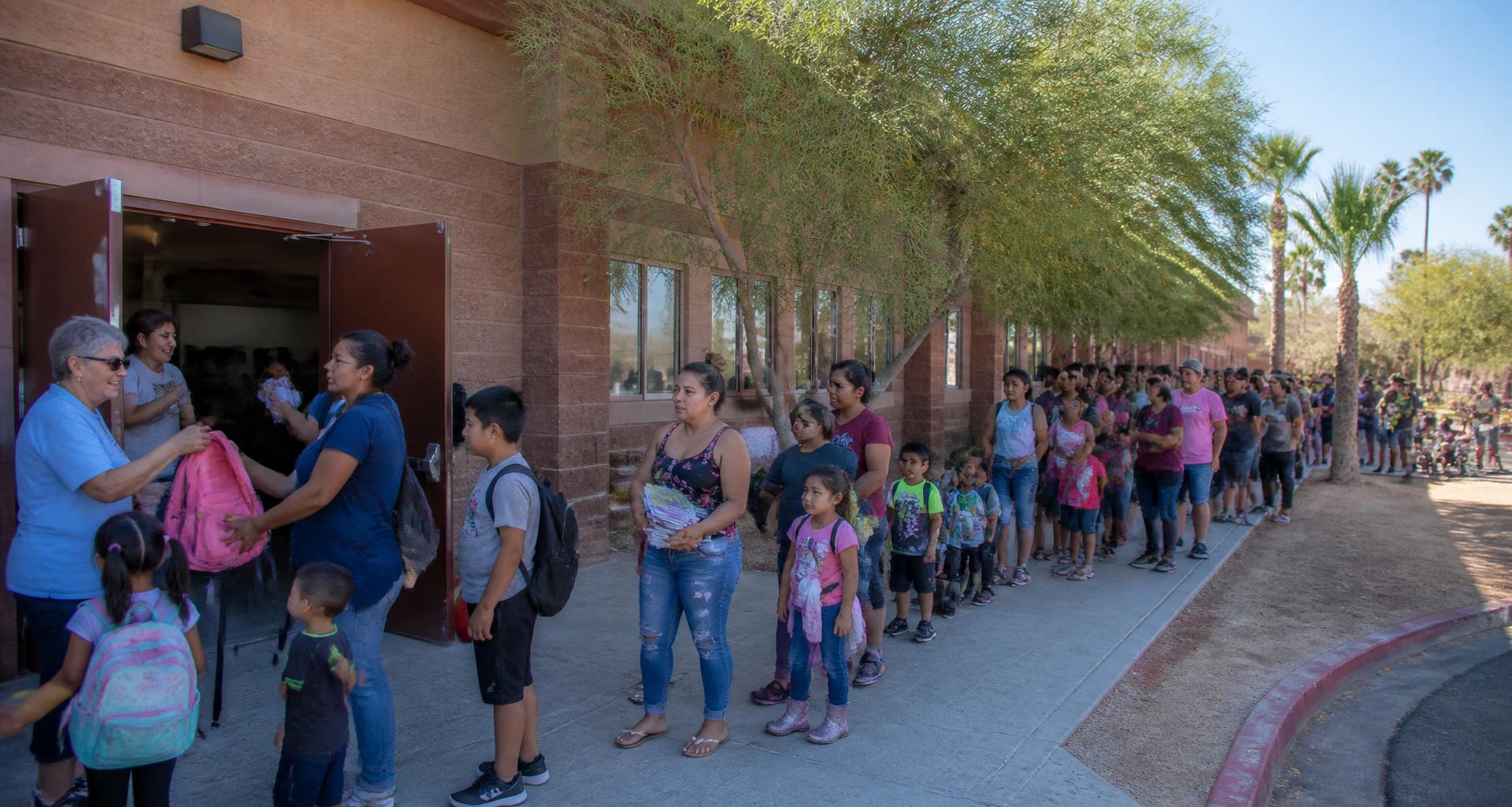 A long line of Southern Nevada families waits outside a community center for the annual backpack distribution.